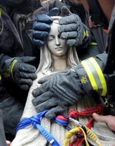 Le mani dei vigili del fuoco proteggono la statua della Madonna rimossa dalla facciata pericolante della chiesa di Paganica (L'Aquila) recuperata dalle macerie del terremoto del 6 aprile, il 13 aprile 2009. ANSA/ DBA